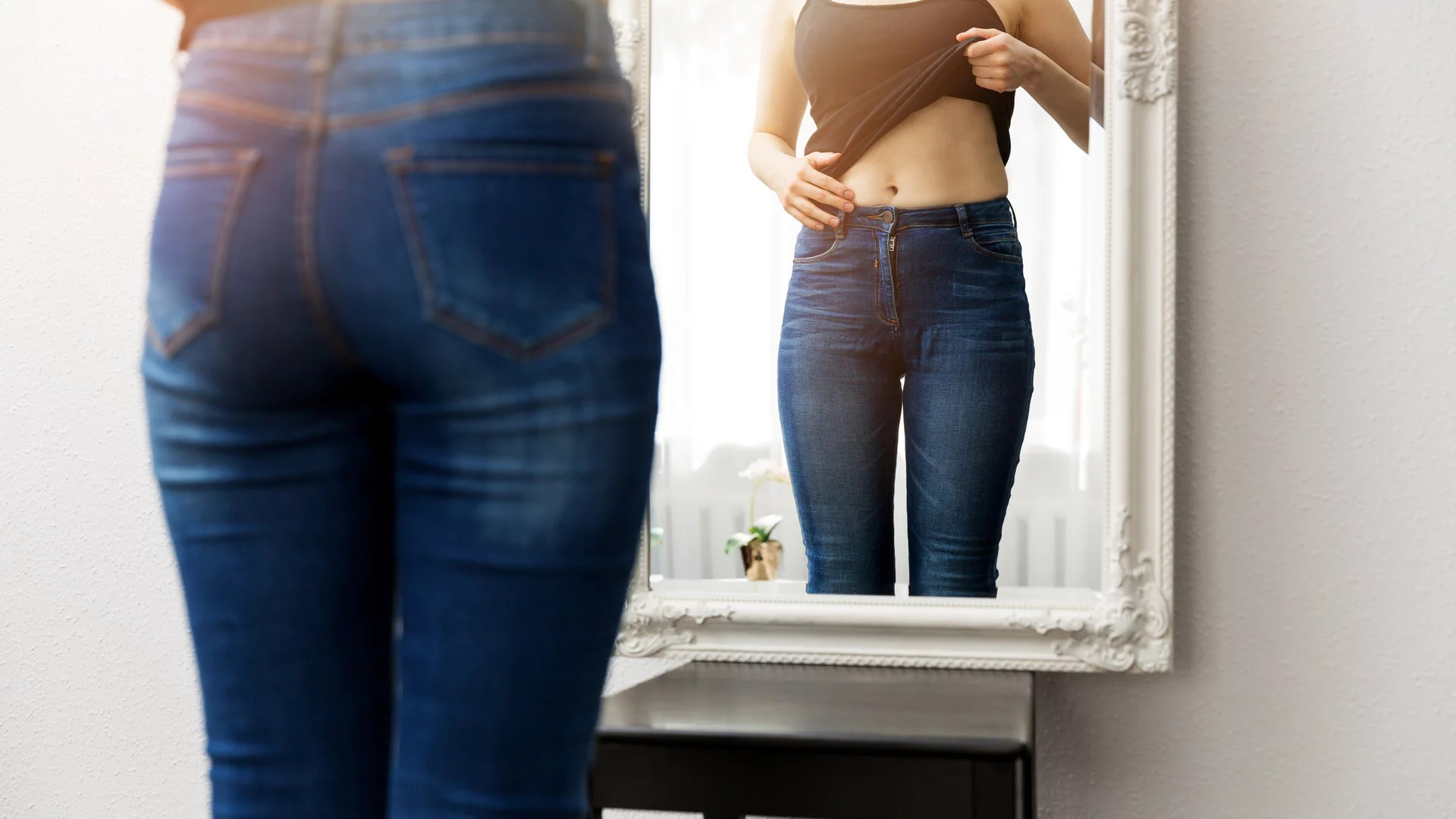 Junge, schlanke Frau vor dem Spiegel